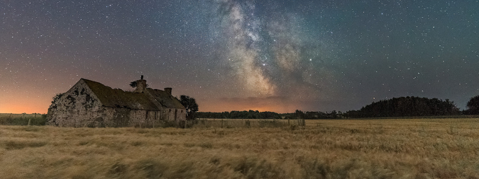 Cabin in a field on a starry night