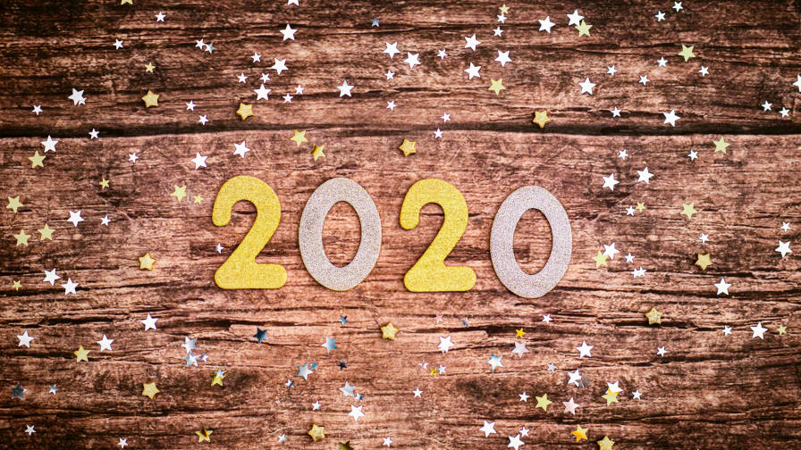 "2020" numbers laid over a wooden table with stars scattered around.