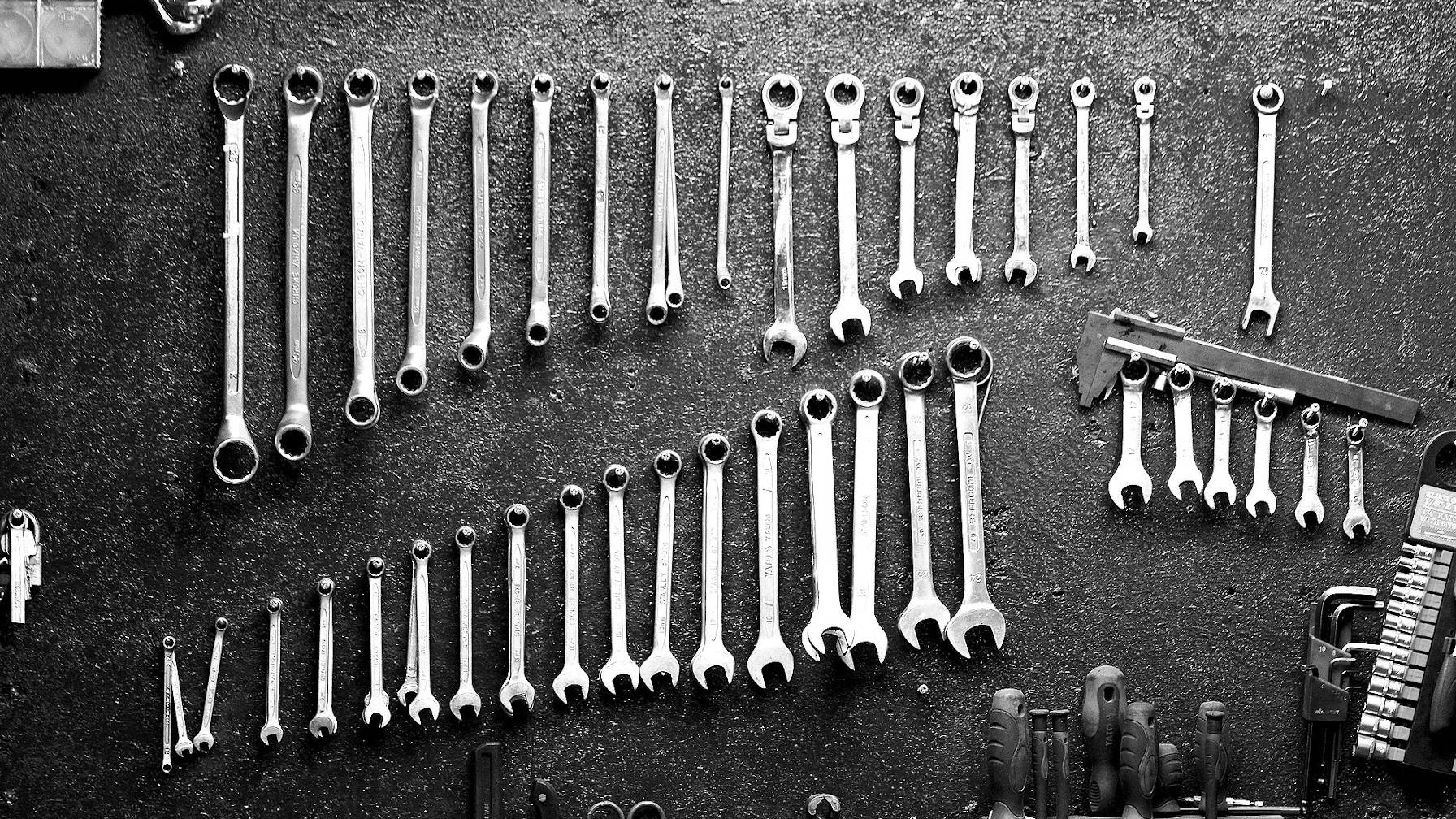 Decorative image of a set of tools, primarily wrenches, neatly aligned.