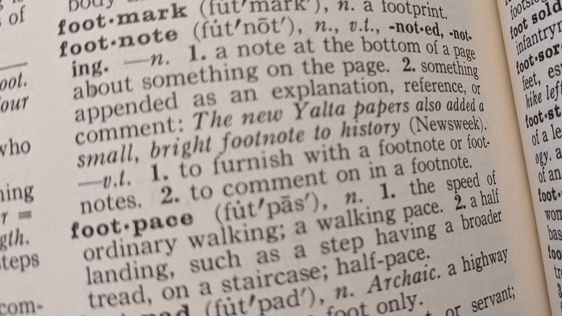 Decorative image of a page in a dictionary, highlighting the "footnote" definition.